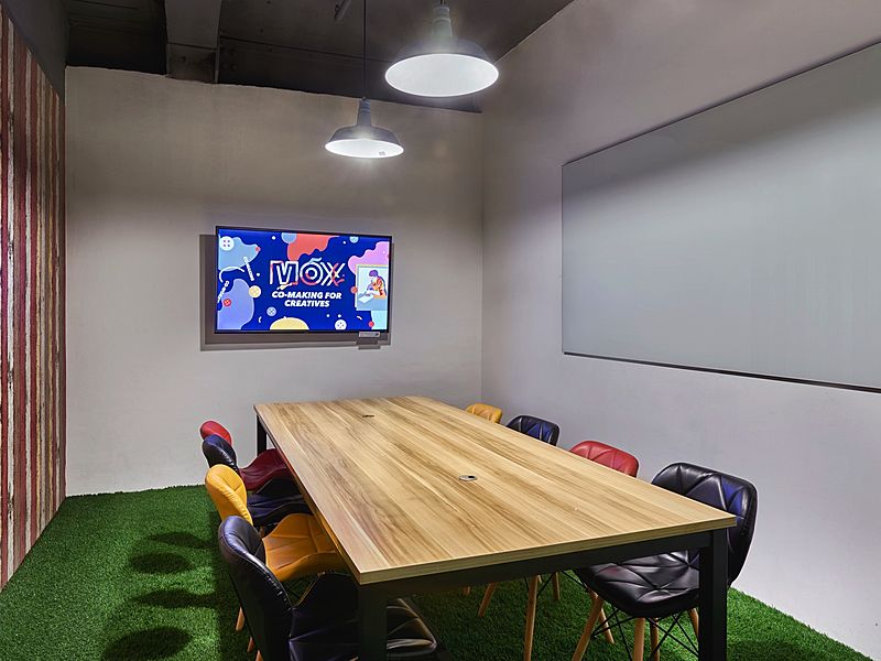 small discussion room in singapore with green floors and tv screen