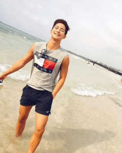 guy at the beach with tank and blue pants