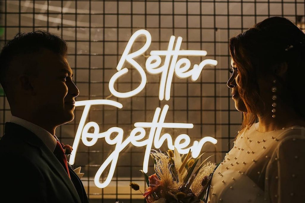 'Better Together' neon lights between a wedding couple smiling at each other